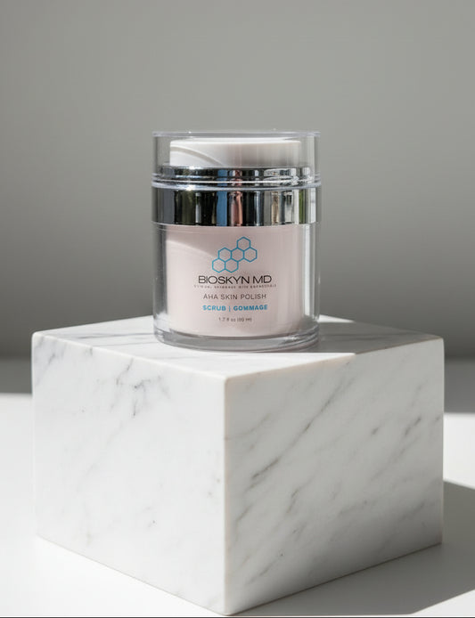 BioSkyn MD AHA Skin Polish exfoliating scrub jar on a white marble block under soft studio lighting.
